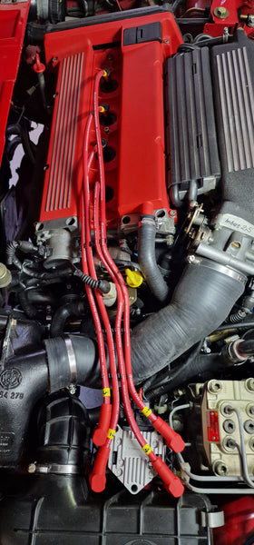 Lancia Delta engine bay with wasted-spark ignition coil and red ignition leads, installation example